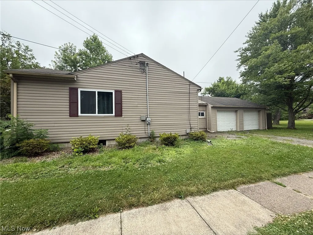 View of property exterior featuring a lawn and a detached garage
