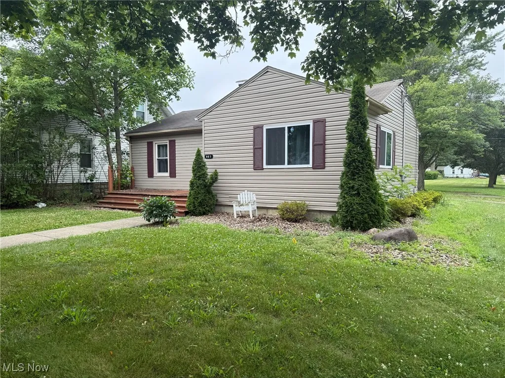 View of front facade featuring a front yard and a wooden deck
