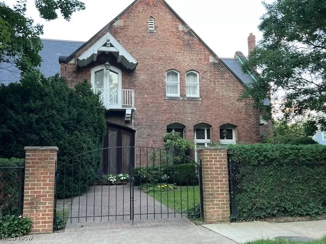 Tudor house featuring brick siding and a fenced front yard