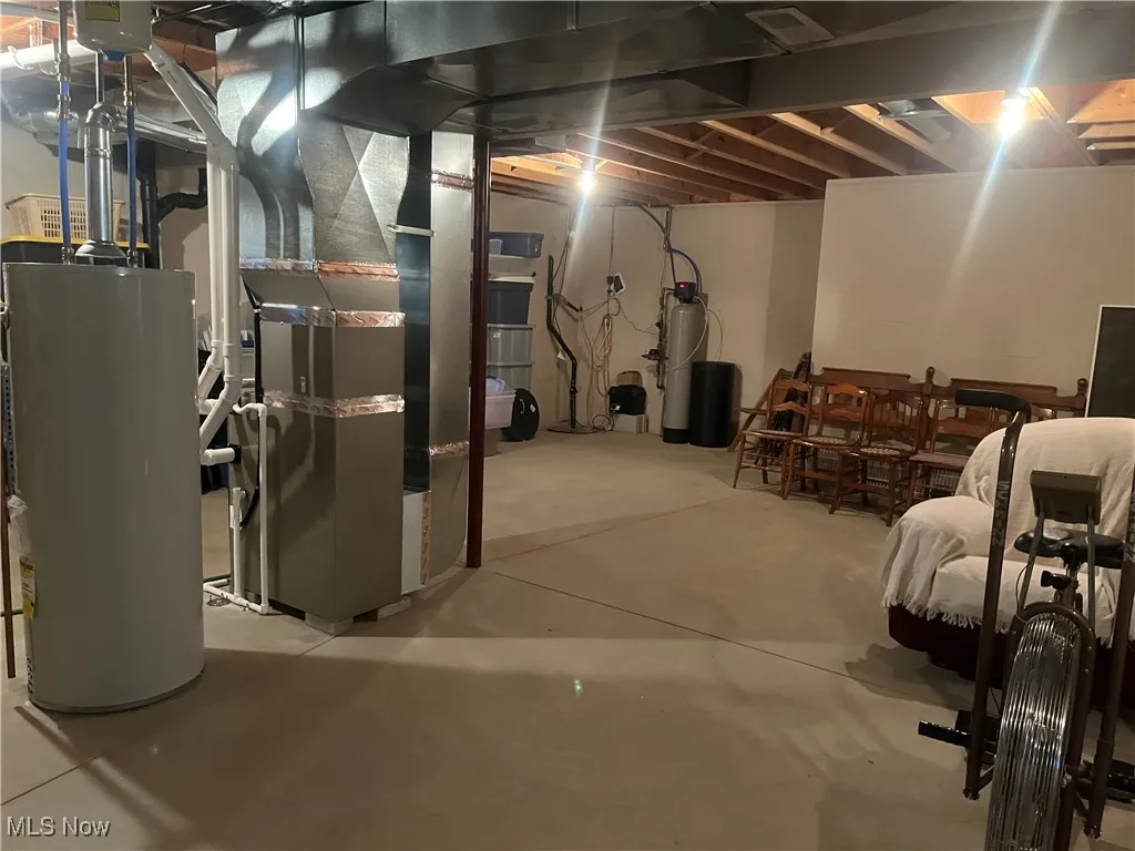 Unfinished basement featuring gas water heater, a water softener, and heating unit