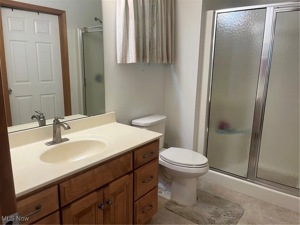 Full bath featuring a shower stall, vanity, and tile patterned floors
