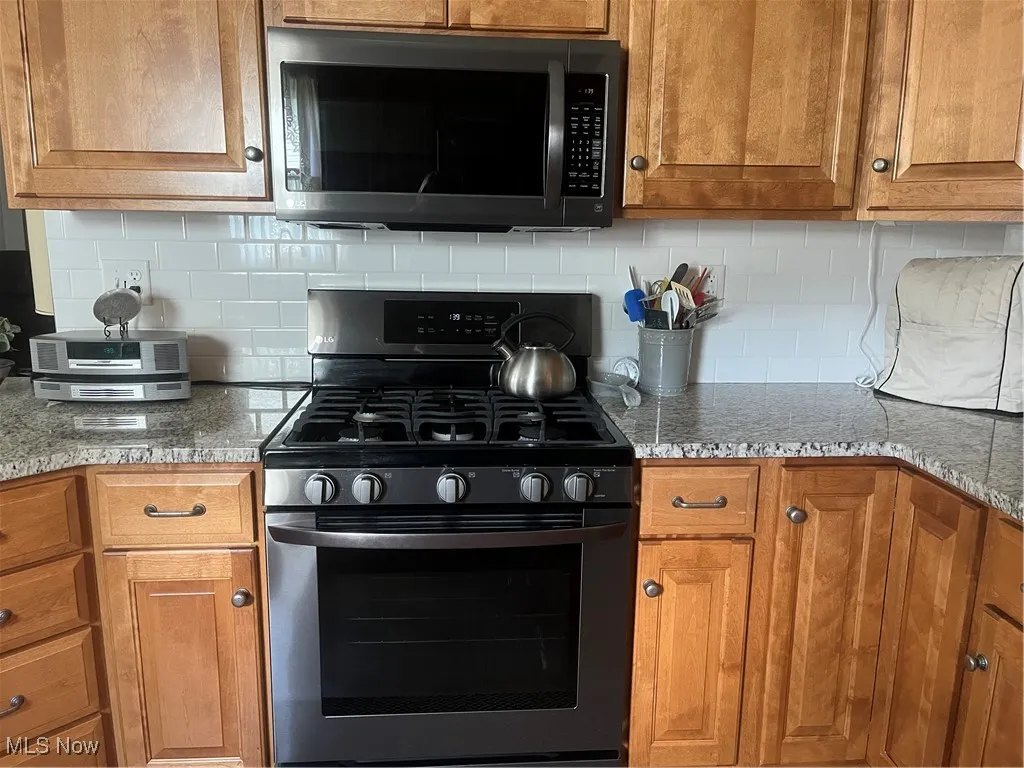 Kitchen with range, brown cabinets, and backsplash