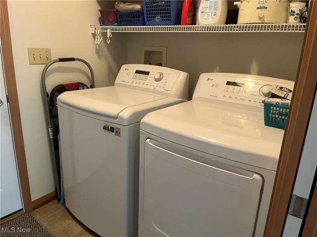 Laundry room with independent washer and dryer and light tile patterned floors