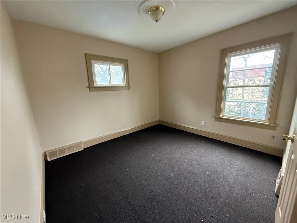 Spare room featuring baseboards and dark colored carpet