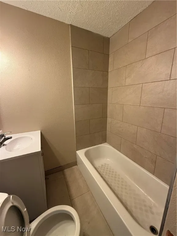 Bathroom featuring a textured ceiling, a bathtub, vanity, tile patterned flooring, and a shower