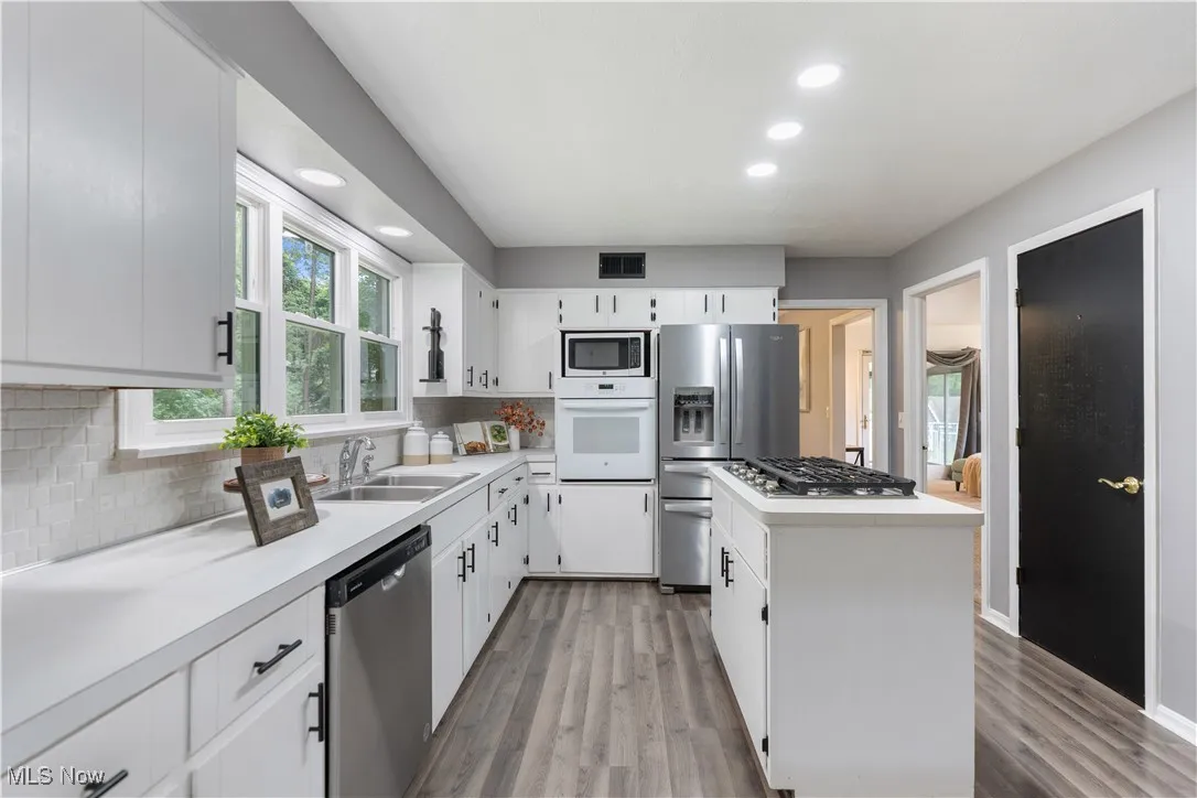 Kitchen featuring stainless steel appliances, a center island, tasteful backsplash, light countertops, and recessed lighting