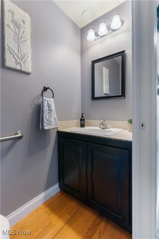 Half bathroom with wood finished floors and vanity