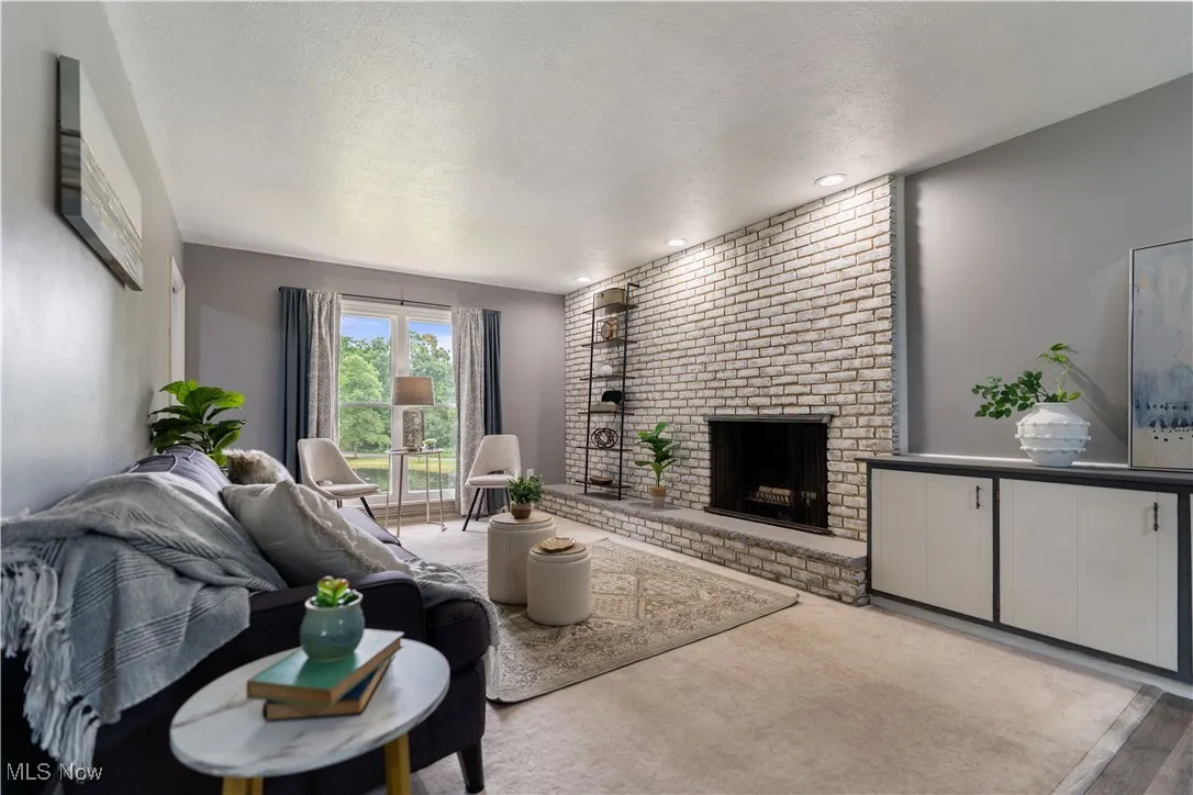 Living area featuring a brick fireplace, a textured ceiling, recessed lighting, and wood finished floors