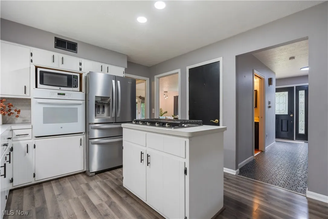 Kitchen featuring stainless steel appliances, a center island, dark wood-style flooring, recessed lighting, and light countertops