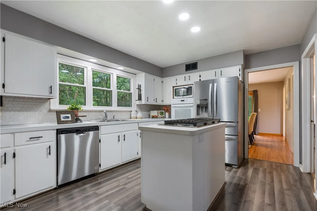 Kitchen featuring stainless steel appliances, dark wood-type flooring, tasteful backsplash, light countertops, and recessed lighting