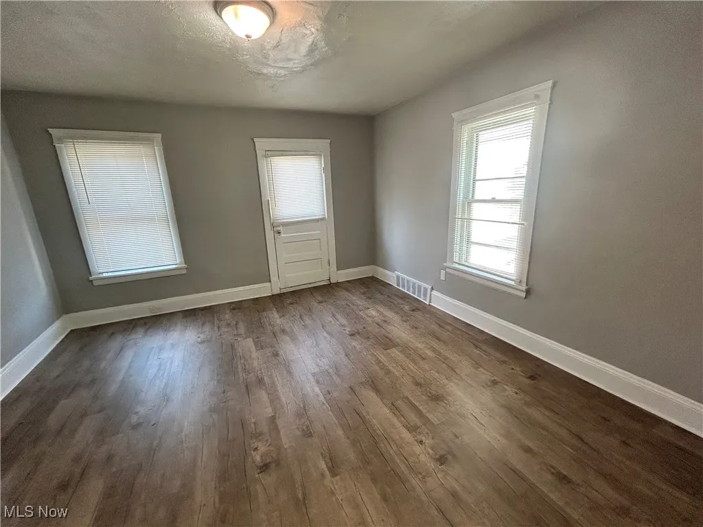 Spare room with dark wood finished floors and baseboards