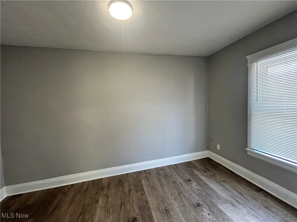 Unfurnished room featuring dark wood-style flooring and baseboards