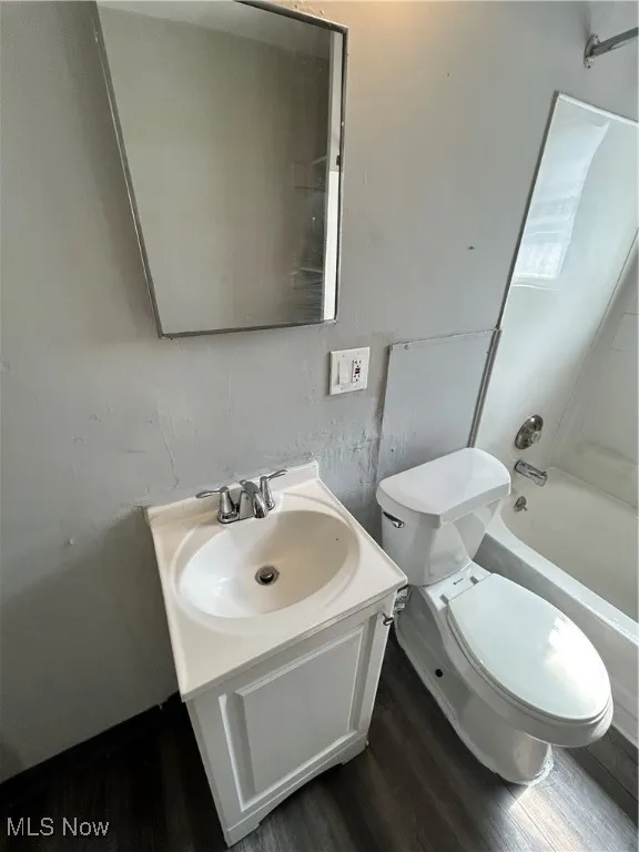Bathroom with wood finished floors, vanity, and bathing tub / shower combination