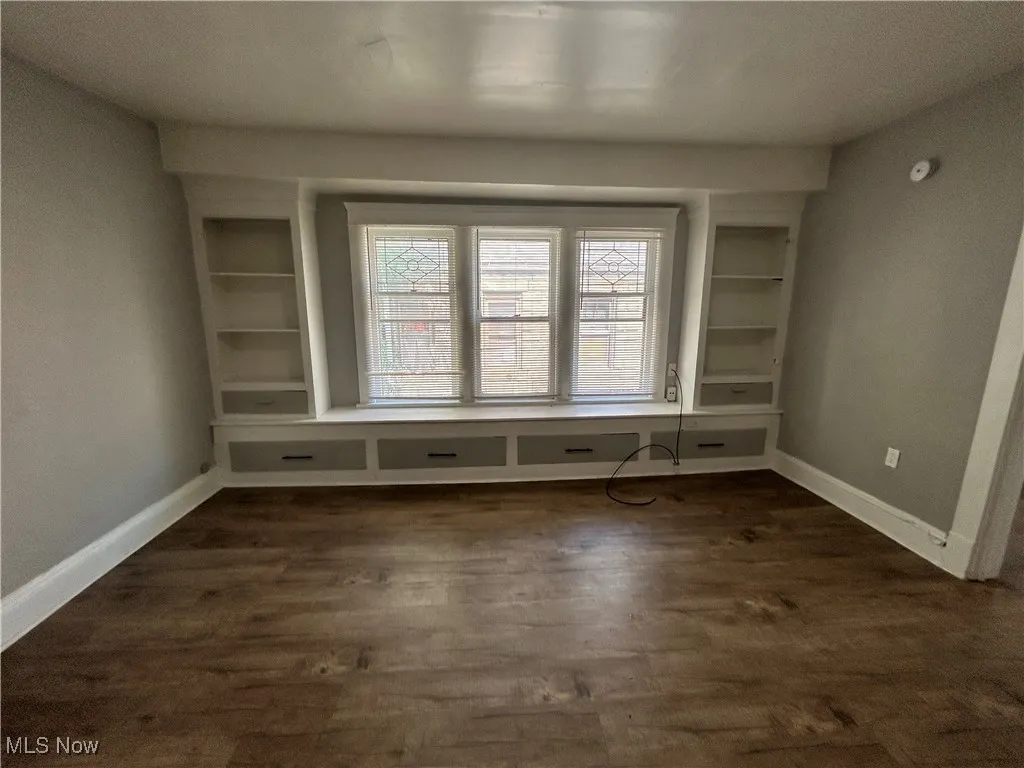 Spare room with built in features and dark wood-type flooring