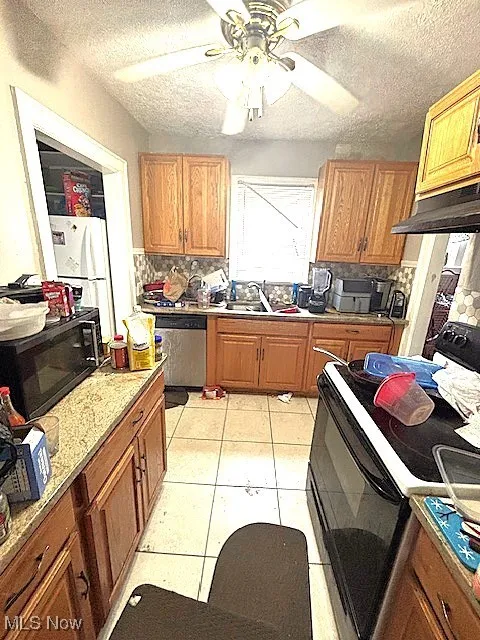 Kitchen featuring black appliances, ceiling fan, decorative backsplash, a textured ceiling, and light tile patterned floors