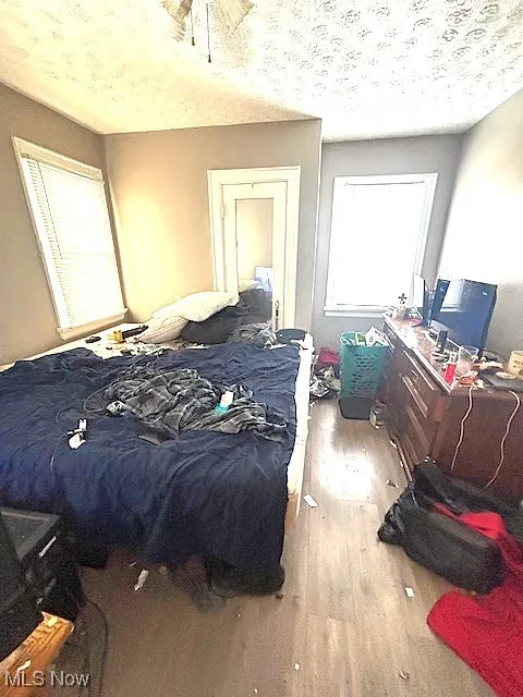 Bedroom with wood finished floors and a textured ceiling