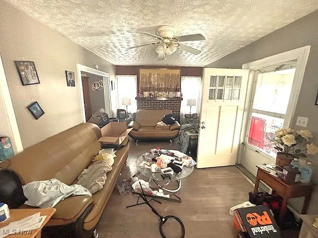 Living room featuring a textured ceiling, ceiling fan, and wood finished floors