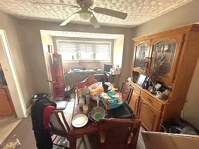 Dining room featuring a ceiling fan and a textured ceiling