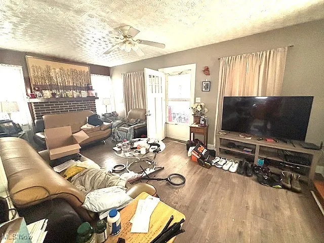Living room featuring wood finished floors, ceiling fan, and a textured ceiling