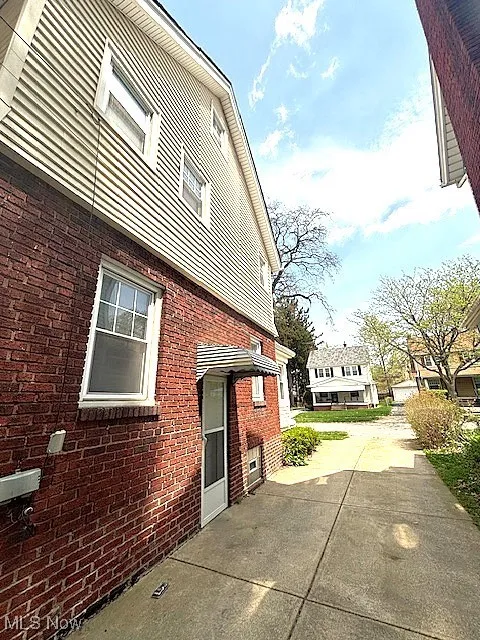 View of side of home featuring brick siding and a patio