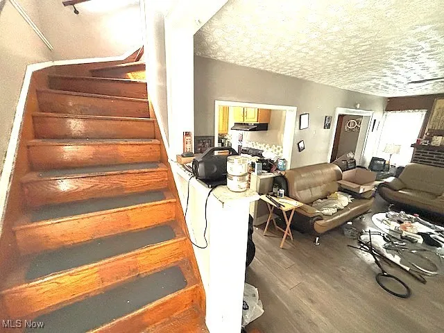 Stairs featuring wood finished floors and a textured ceiling