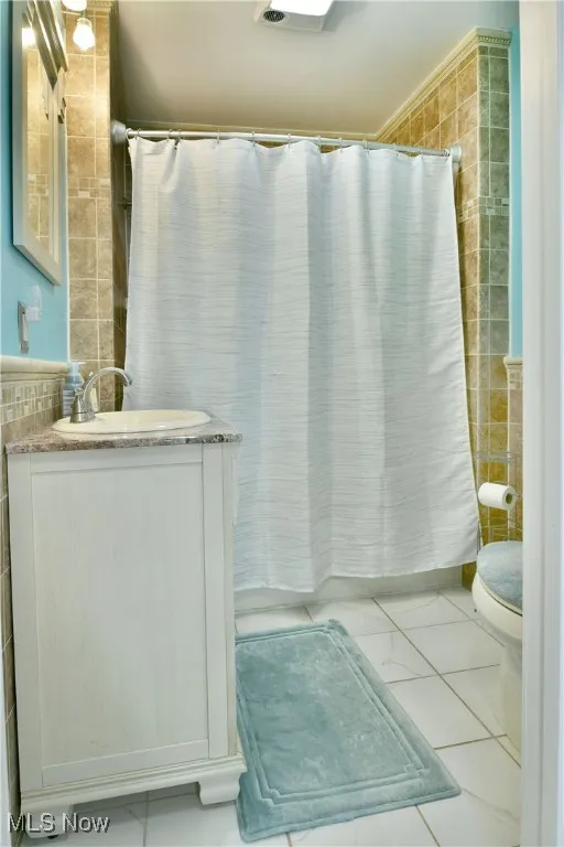 Full bath with tile walls, vanity, and a shower with curtain