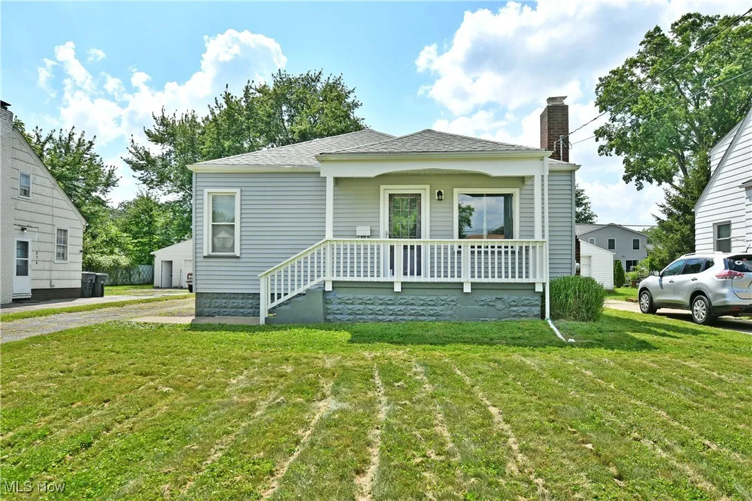 Bungalow-style home with a chimney, covered porch, a front yard, and roof with shingles