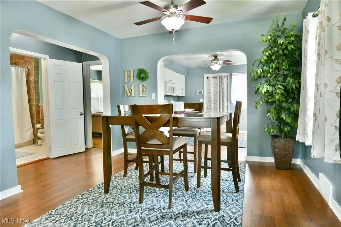 Dining space with a ceiling fan, wood finished floors, and arched walkways