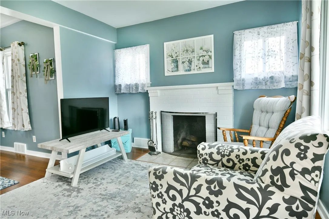 Living area featuring plenty of natural light, a brick fireplace, and wood finished floors