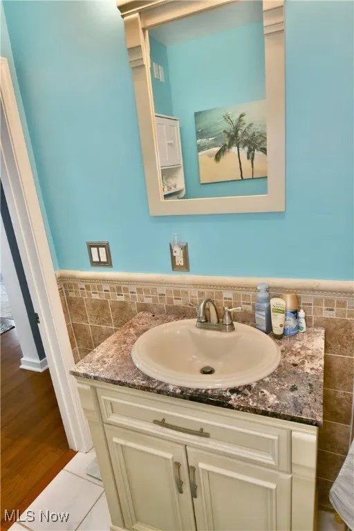 Bathroom with tile walls, vanity, and a wainscoted wall