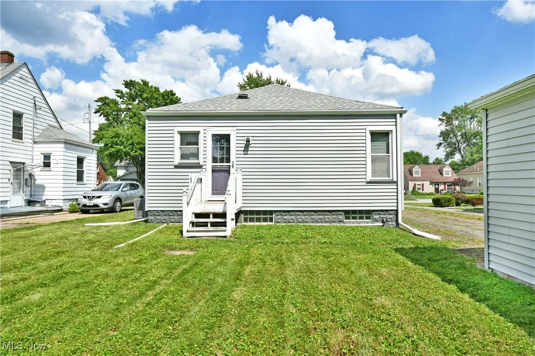 Rear view of house with a yard and entry steps