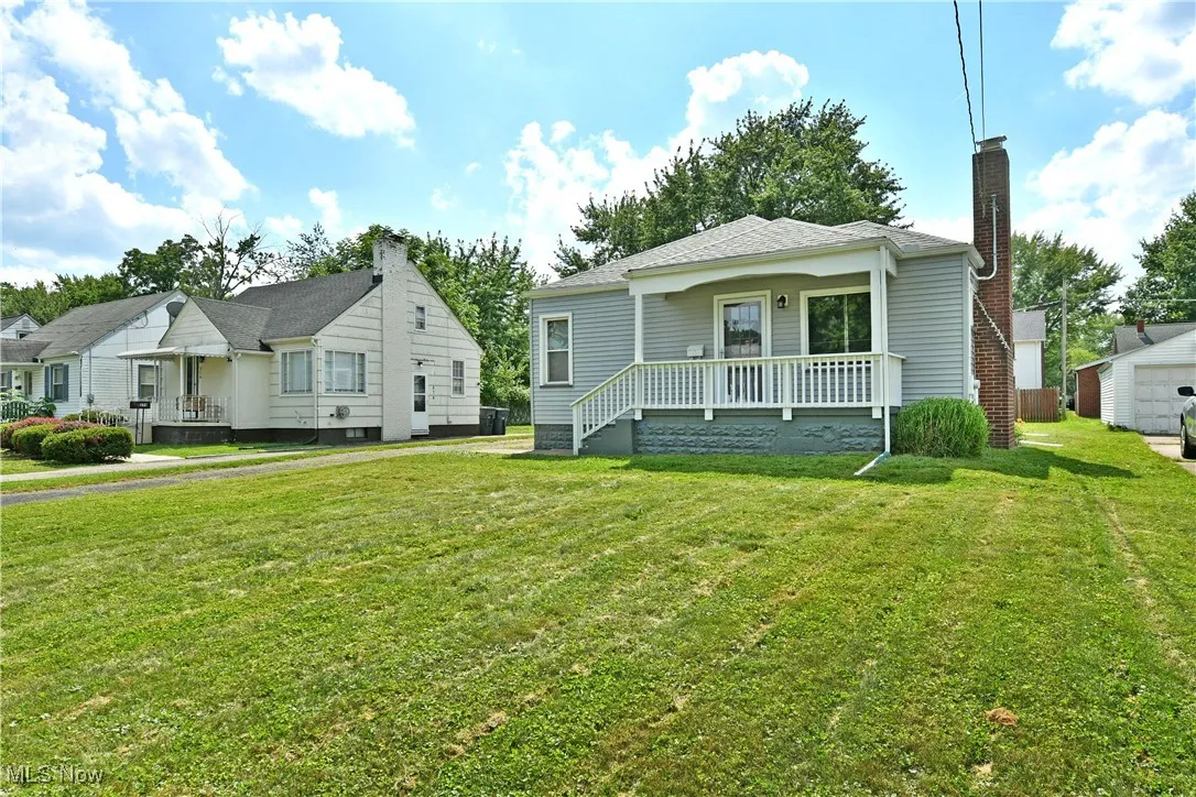 Bungalow with a front lawn, a chimney, and covered porch