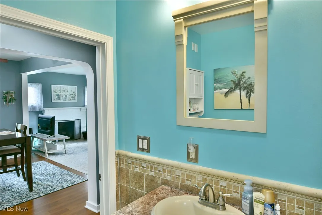 Bathroom featuring a fireplace, wood finished floors, vanity, and a wainscoted wall