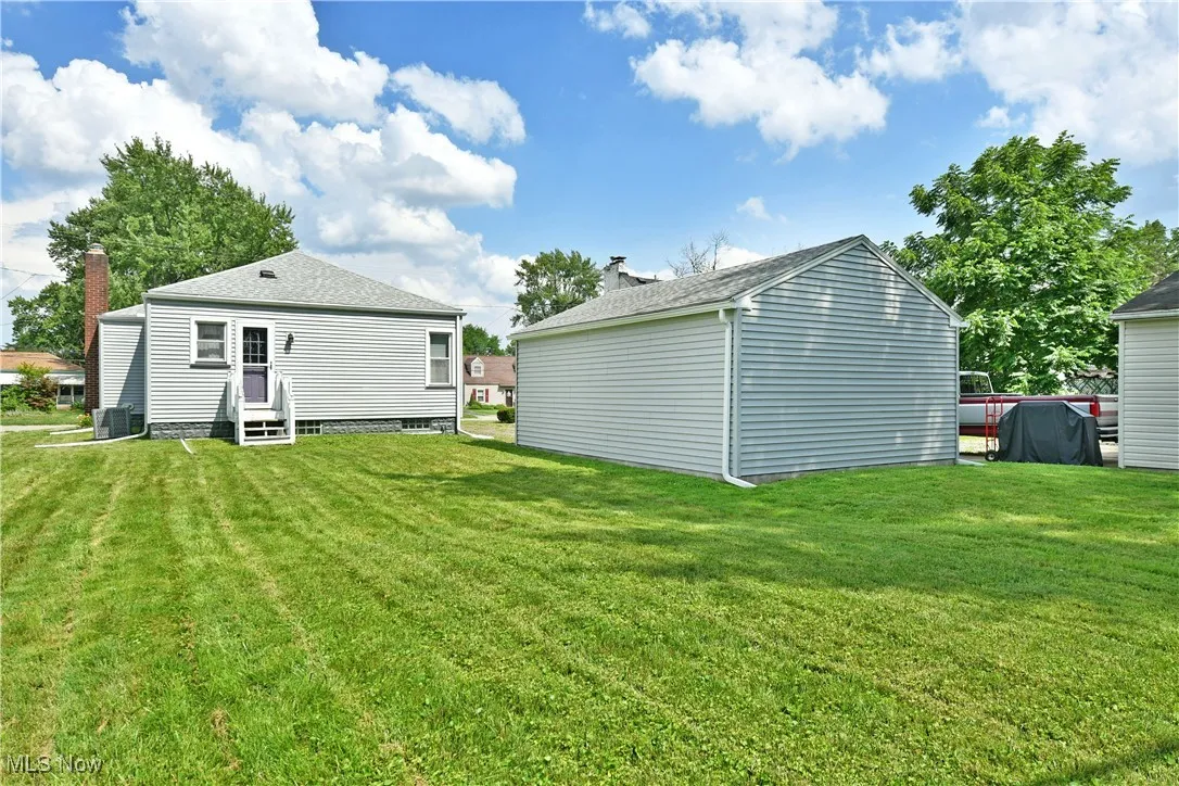 Back of house with entry steps, a yard, and an outbuilding