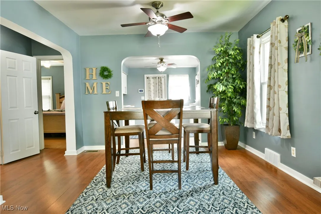 Dining area featuring arched walkways, a ceiling fan, and wood finished floors