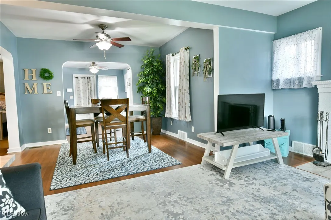 Dining space with arched walkways, a ceiling fan, and wood finished floors
