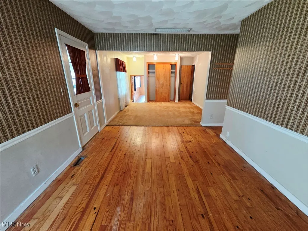 Hall with wallpapered walls and wood-type flooring