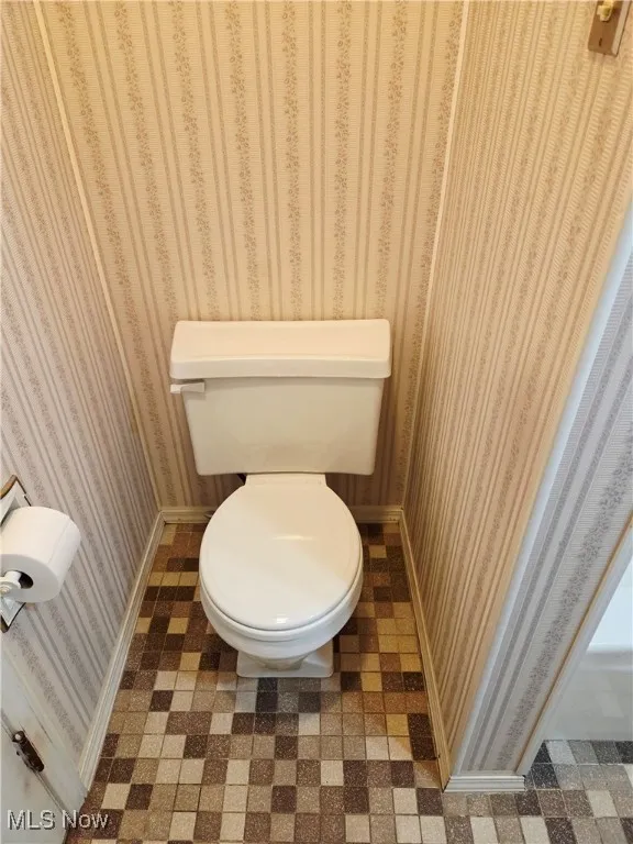 Bathroom with tile patterned floors and wallpapered walls