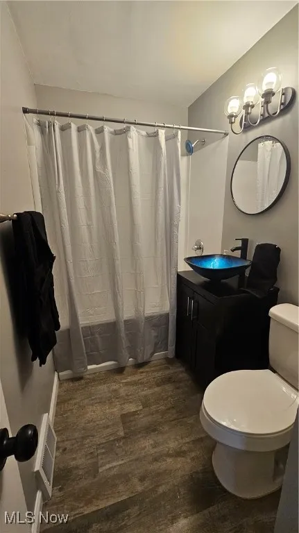 Bathroom featuring wood finished floors, vanity, and shower / bath combo