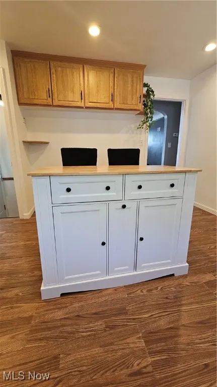 Kitchen with light countertops, dark wood-style flooring, recessed lighting, refrigerator, and a peninsula