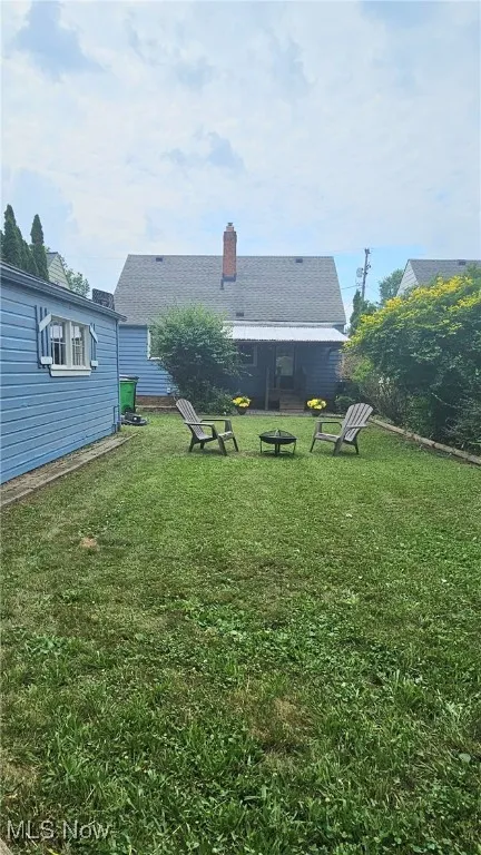 Rear view of house featuring a yard and a chimney