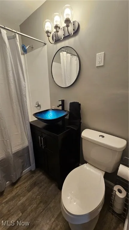 Bathroom with wood finished floors, vanity, a chandelier, and shower / bathtub combination with curtain