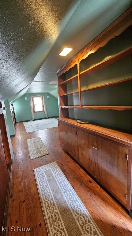 Bonus room featuring hardwood / wood-style flooring, a textured ceiling, and lofted ceiling
