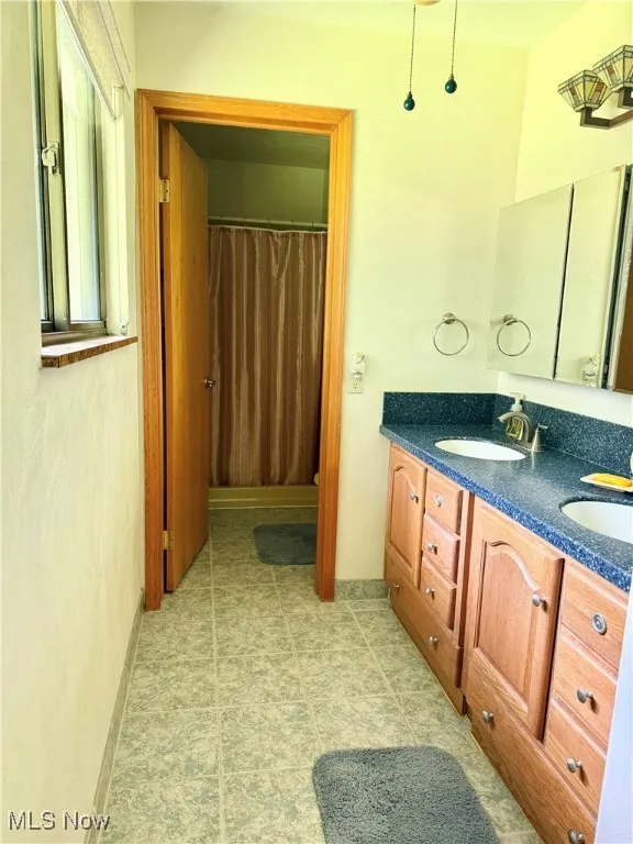 Bathroom featuring double vanity and a shower with curtain