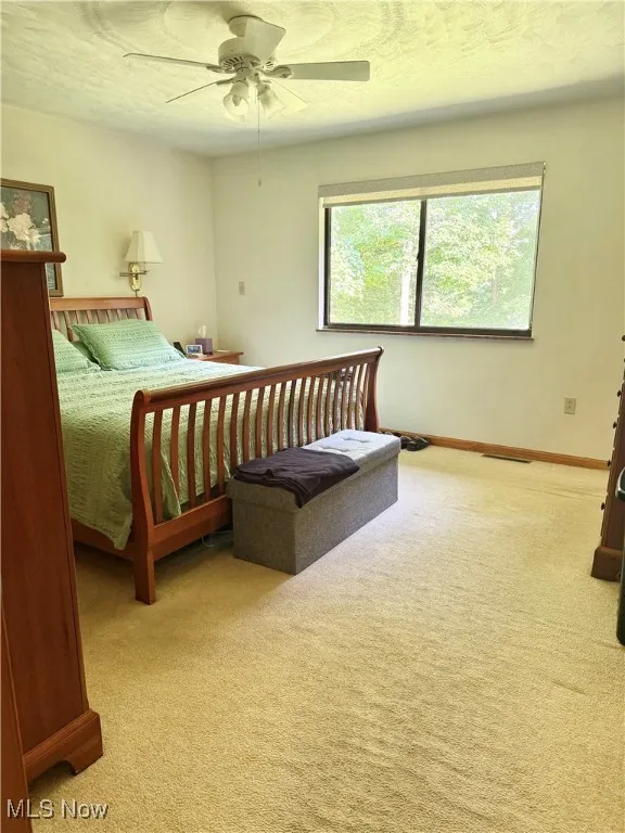 Carpeted bedroom featuring ceiling fan and a textured ceiling