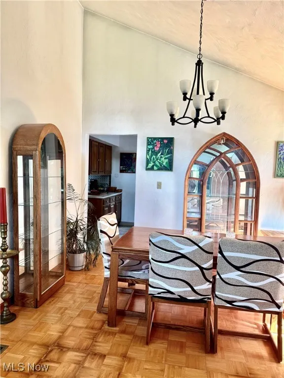 Dining room featuring a chandelier and high vaulted ceiling