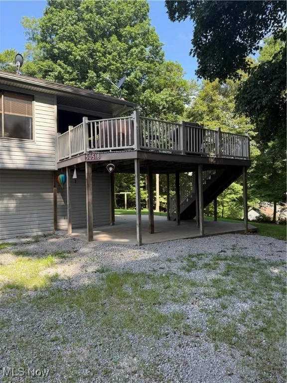 Back of property featuring a wooden deck, a patio, stairway, and a yard