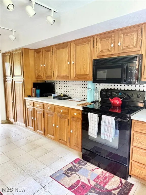 Kitchen featuring black appliances, rail lighting, light countertops, and light tile patterned floors