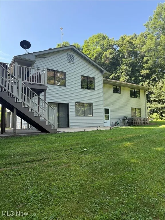 Back of property with stairs, a yard, and a wooden deck