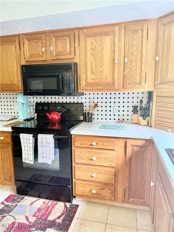 Kitchen featuring black appliances, light countertops, tasteful backsplash, and light tile patterned floors